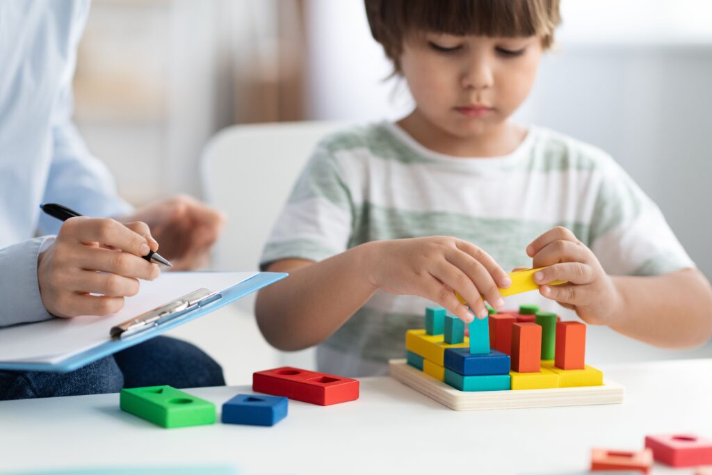 Young boy in therapy session playing with building blocks.